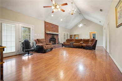 Living area with high vaulted ceiling, beam ceiling, a fireplace, wood finished floors, and healthy amount of natural light
