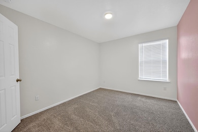 Carpeted spare room featuring baseboards