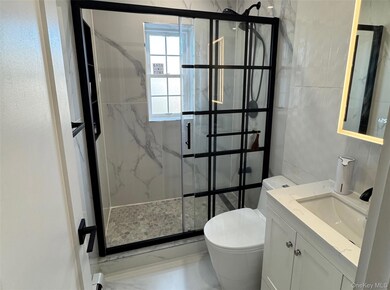 Bathroom featuring vanity and a marble finish shower