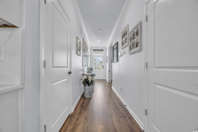 Hall featuring crown molding, dark wood-type flooring, and baseboards