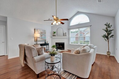 Living room featuring a textured ceiling, ceiling fan, lofted ceiling, dark wood-type flooring, and a fireplace