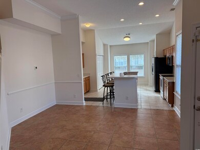 Kitchen with light tile patterned floors, a kitchen breakfast bar, a center island, stainless steel appliances, and a textured ceiling