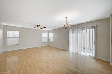 Spare room with a chandelier, light wood finished floors, and ceiling fan