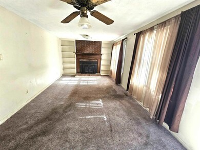 Unfurnished living room with built in features, a textured ceiling, carpet, baseboards, and ceiling fan