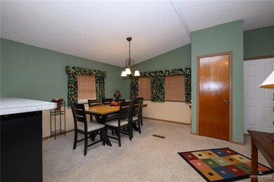 Dining room with baseboards, light carpet, vaulted ceiling, and a notable chandelier