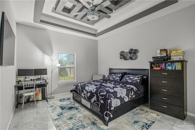 Bedroom featuring a raised ceiling, an office area, and ceiling fan