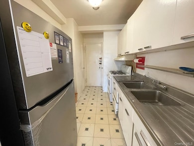 Kitchen with under cabinet range hood, freestanding refrigerator, white cabinets, white range with gas stovetop, and light floors