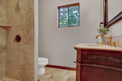 The first-floor bath features travertine tile, a w