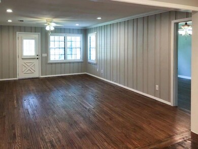 Spacious living room featuring ceiling fan, dark wood-type flooring, and a healthy amount of sunlight