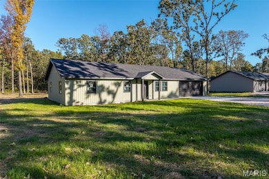 View of front facade with a front lawn, a shingled roof, driveway, and view of scattered trees