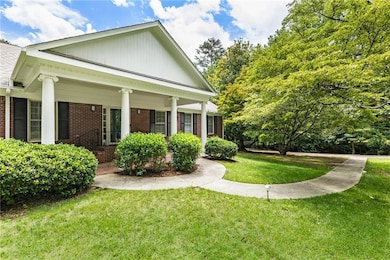 View of side of property featuring brick siding, a lawn, and covered porch