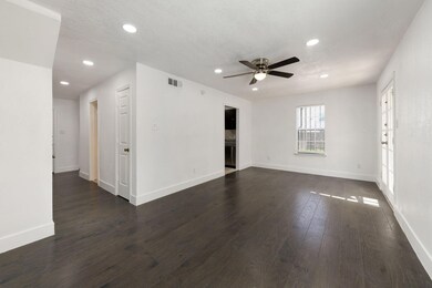 Unfurnished room featuring a ceiling fan, dark woo