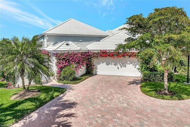 View of front of property with decorative driveway, a front lawn, a tiled roof, and an attached garage