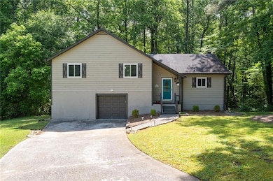Tri-level home featuring concrete driveway, a front lawn, a garage, and a shingled roof