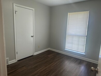 Empty room featuring dark wood finished floors and baseboards
