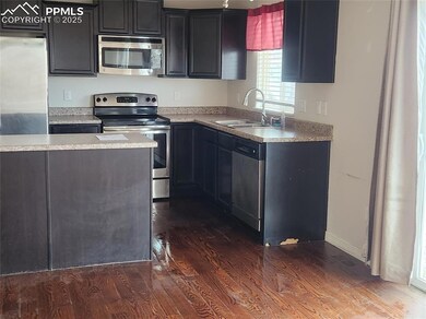 Kitchen featuring stainless steel appliances, dark wood-style flooring, a sink, and light countertops