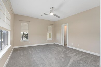 Carpeted empty room featuring a ceiling fan and b