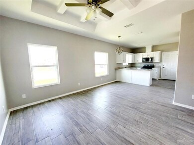 Kitchen with appliances with stainless steel finishes, open floor plan, a peninsula, white cabinets, and ceiling fan