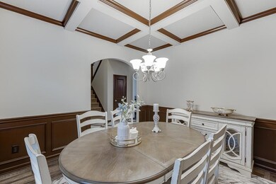 Dining space with coffered ceiling, stairs, beam ceiling, a wainscoted wall, and a decorative wall