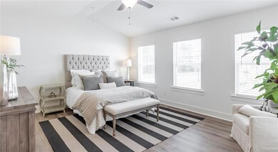 Bedroom featuring multiple windows, lofted ceiling, wood finished floors, ceiling fan, and baseboards