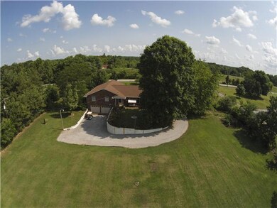 Rear view of home with large driveway that wraps to rear entry garage