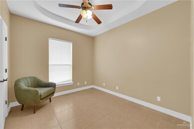 Living area with light tile patterned flooring, a tray ceiling, and a ceiling fan