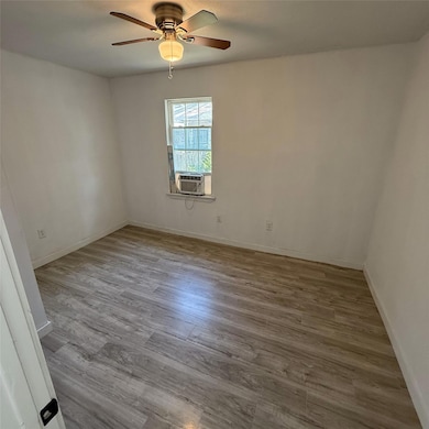 Unfurnished room featuring cooling unit, wood fini