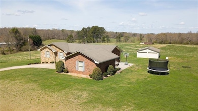 View of side of property with a trampoline, a lawn, and brick siding