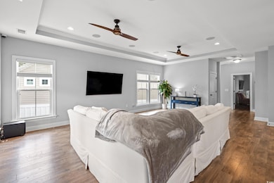Living room featuring a tray ceiling, hardwood / wood-style flooring, a ceiling fan, and recessed lighting