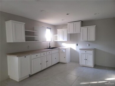 Kitchen featuring white cabinetry, light countertops, open shelves, and light tile patterned floors