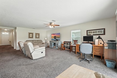 Home office with light carpet, ceiling fan, and a textured ceiling