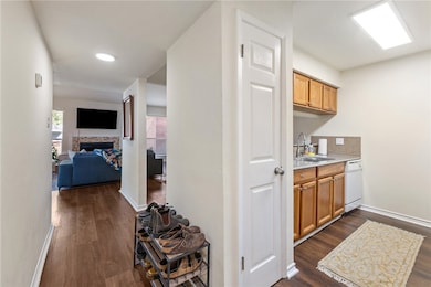 Bar area featuring light countertops, brown cabinets, dark wood finished floors, a fireplace, and white dishwasher