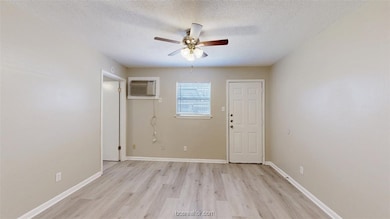 Unfurnished room with a wall unit AC, a textured c