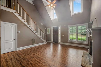 Foyer featuring stairs, a towering ceiling, plenty of natural light, wood finished floors, and a ceiling fan