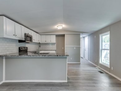 Kitchen featuring dark stone counters, light hardw