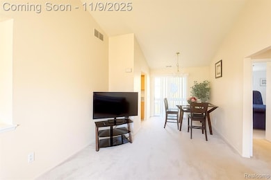 Carpeted dining area featuring a chandelier and lofted ceiling
