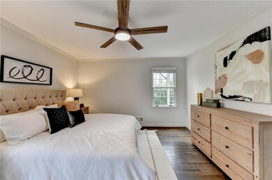 Bedroom featuring crown molding, dark wood-type flooring, and a ceiling fan