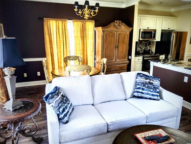 Living area featuring dark wood finished floors, crown molding, and a chandelier