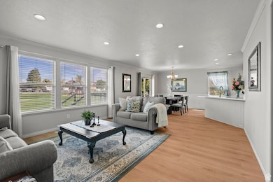 Living area with ornamental molding, light wood-style flooring, recessed lighting, a textured ceiling, and a chandelier