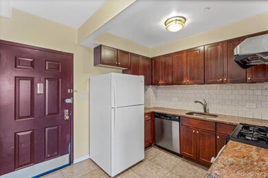 Kitchen featuring freestanding refrigerator, tasteful backsplash, light stone countertops, stainless steel dishwasher, and light tile patterned floors