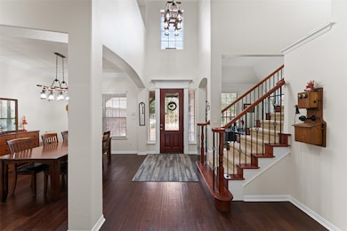 Foyer entrance with arched walkways, a chandelier, hardwood / wood-style floors, a towering ceiling, and stairway