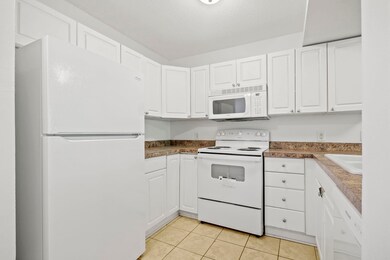 Kitchen with white appliances, white cabinets, and