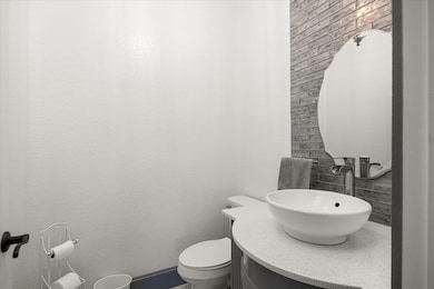 Downstairs half bathroom featuring vanity and toilet