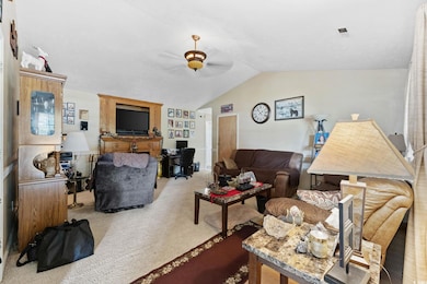 Living area featuring ceiling fan, lofted ceiling, and carpet floors