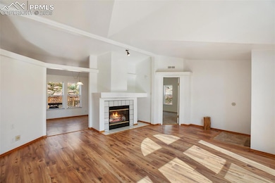 Unfurnished living room with vaulted ceiling, a fireplace, and wood finished floors