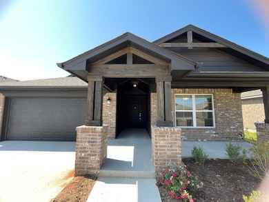 View of front facade featuring brick siding, driveway, covered porch, and an attached garage