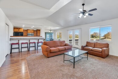 Living room with lofted ceiling, a ceiling fan, light wood-style floors, and recessed lighting