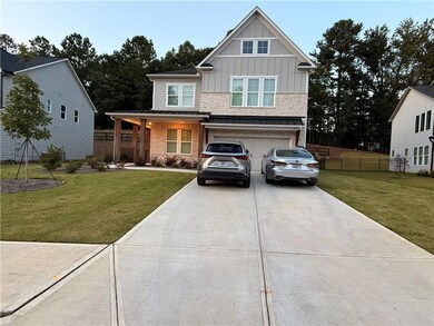 View of front of house with board and batten siding, a porch, driveway, a garage, and brick siding