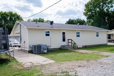 Back of house featuring a trampoline, a yard, crawl space, and a shingled roof