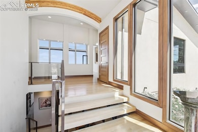 Foyer surrounded by tall windows, wood beamed arched ceilings and a floating staircase